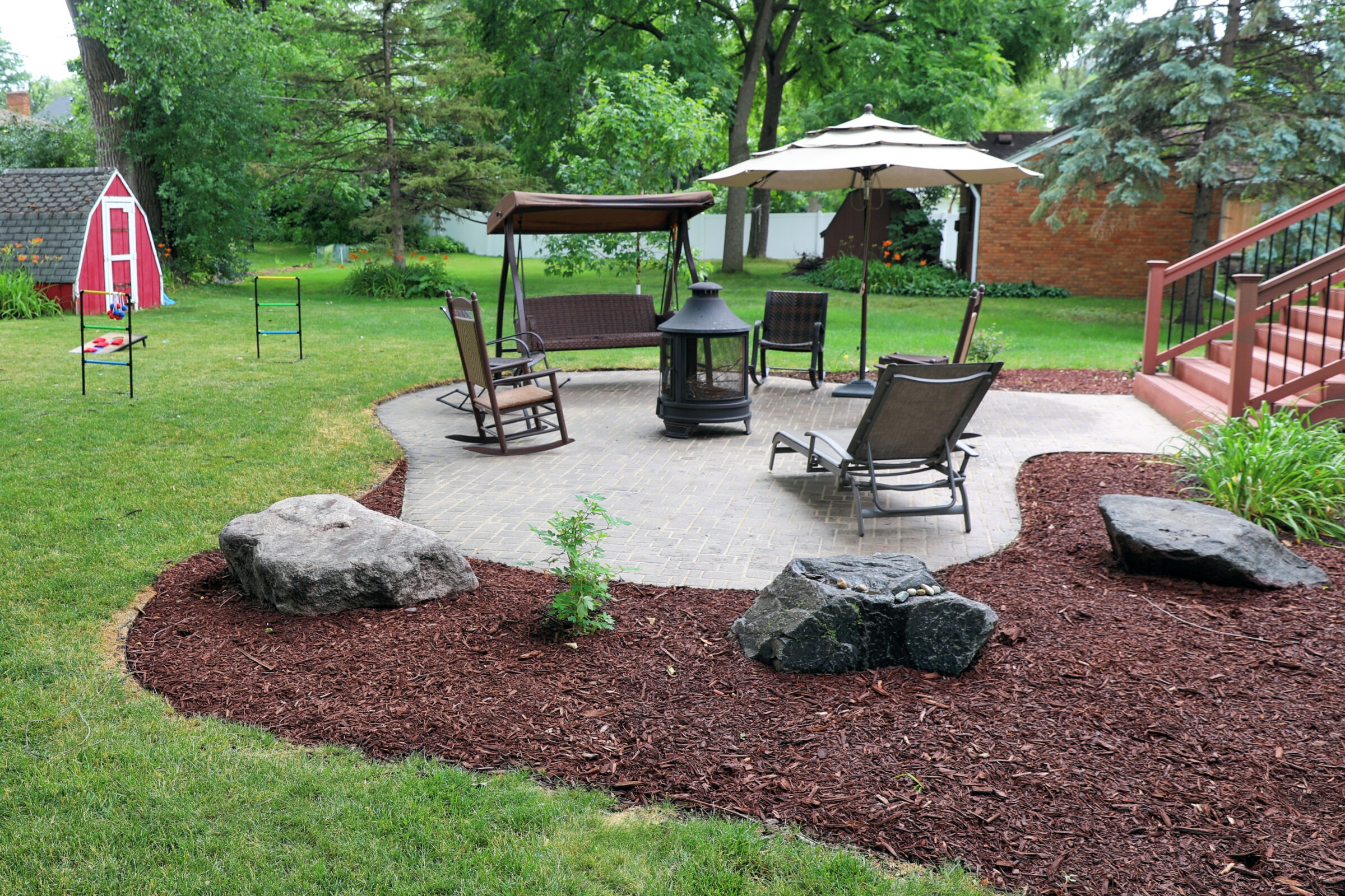 Backyard landscaping ideas using a custom patio and well-placed mulch.