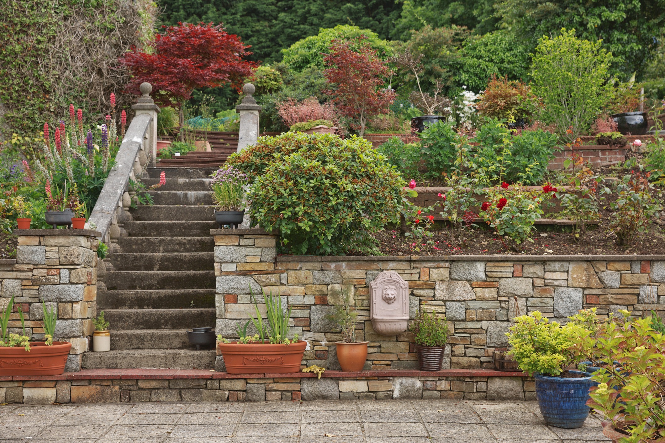 Natural stone steps and retaining wall, planter and garden border framing home entrance. Beautiful hardscape, colorful landscape design.