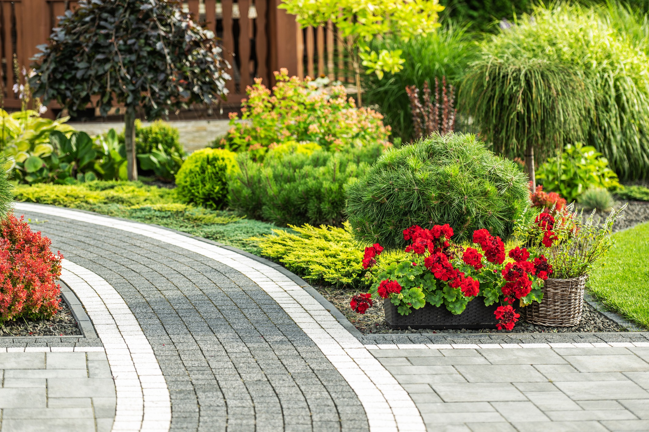 A beautifully landscaped garden features a winding stone pathway bordered by colorful flowers and greenery.