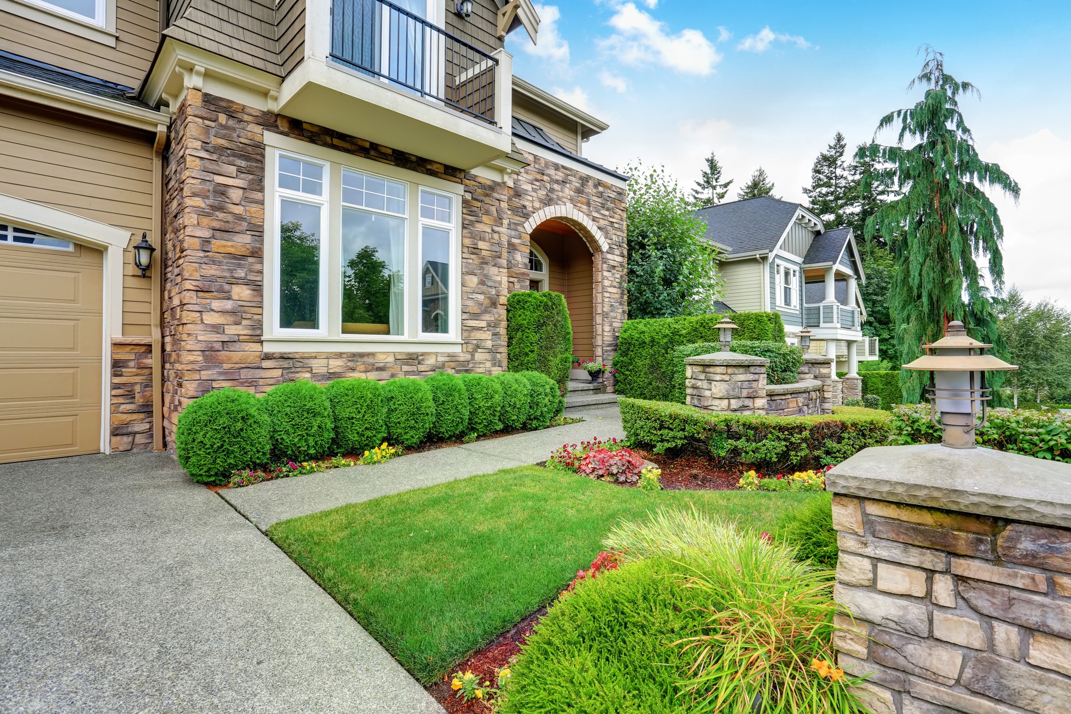 Beautiful curb appeal of American house with stone trim and perfectly trimmed shrubs