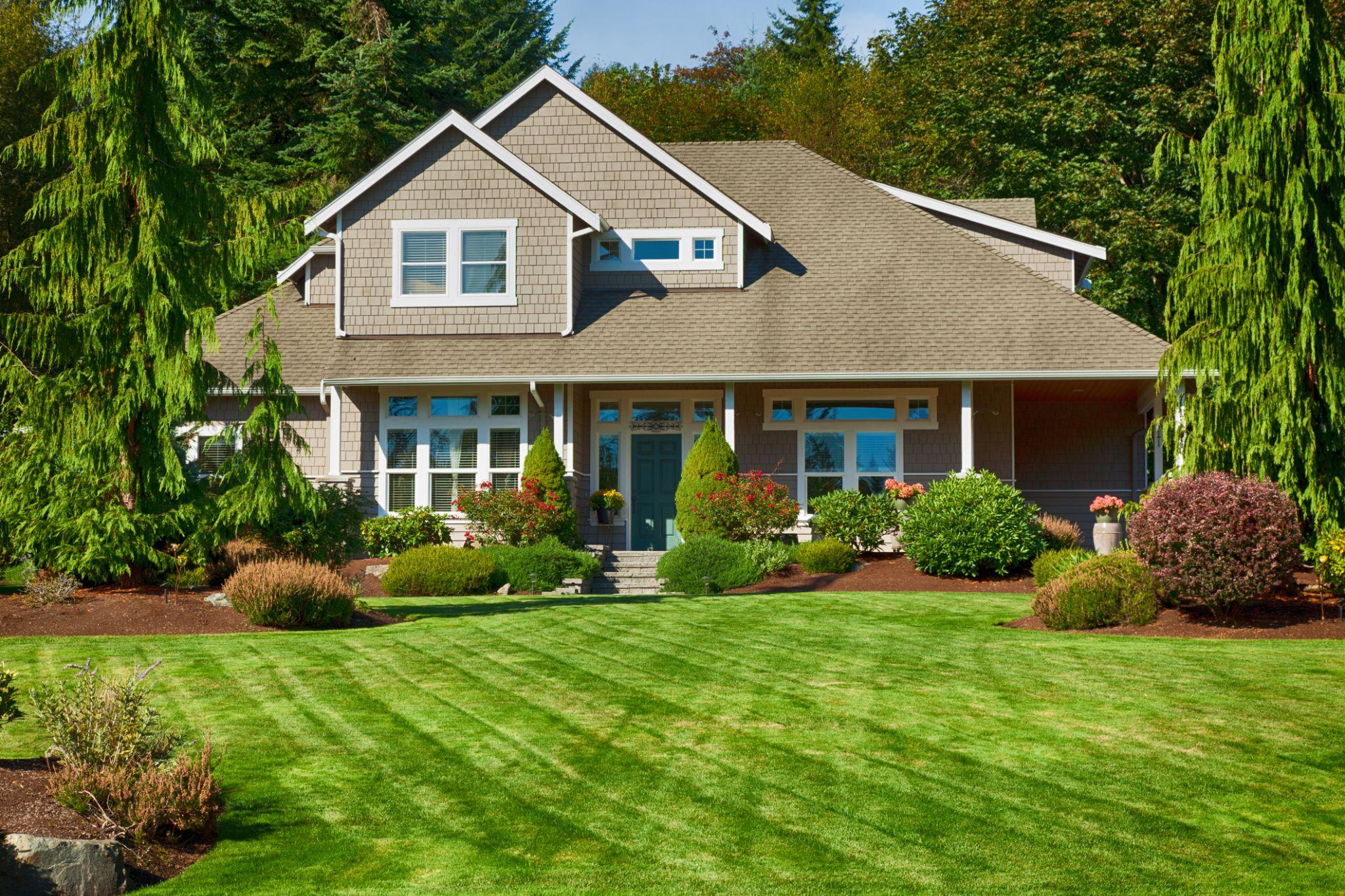 Large home with striped lawn and landscaped front yard